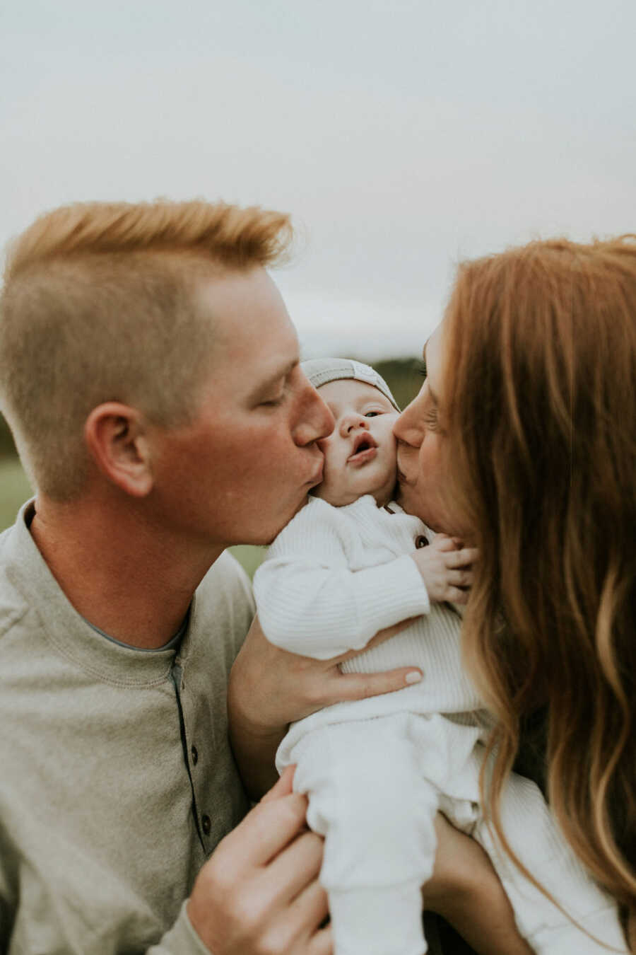 parents kissing their adopted son