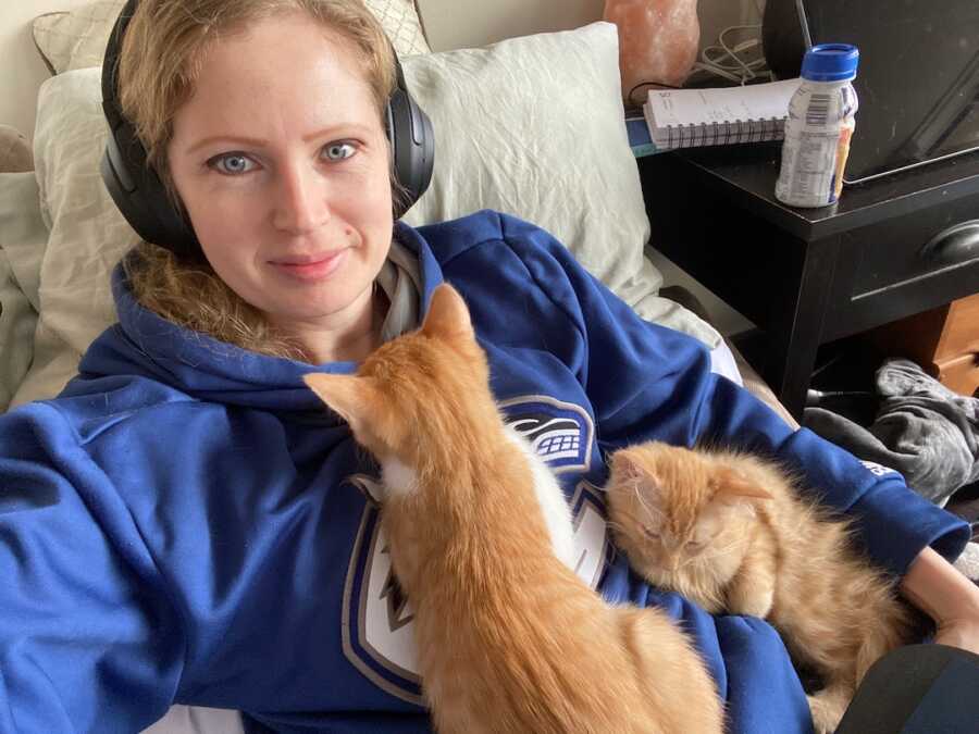 woman lying with her two orange cats 