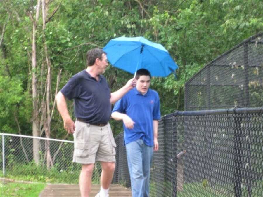 dad holding an umbrella over his child