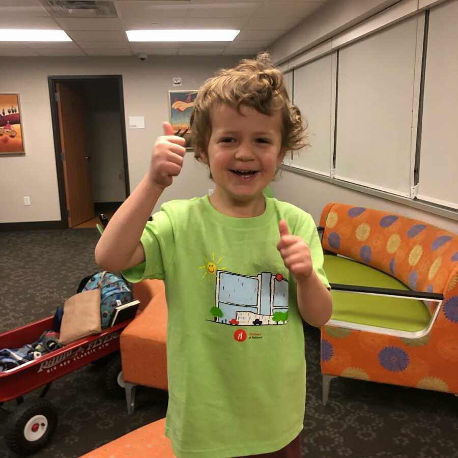 little boy in green shirt with thumbs up 