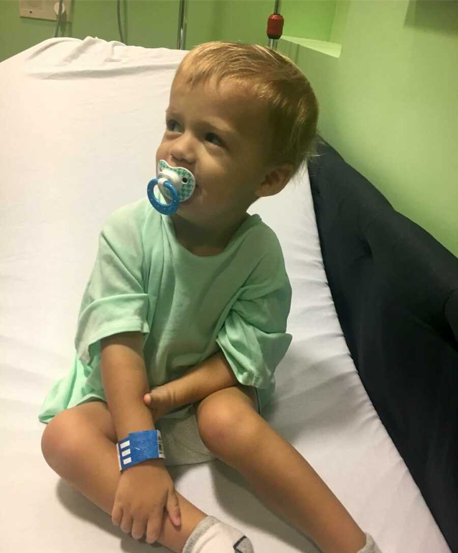 little boy in hospital gown sitting in hospital bed 