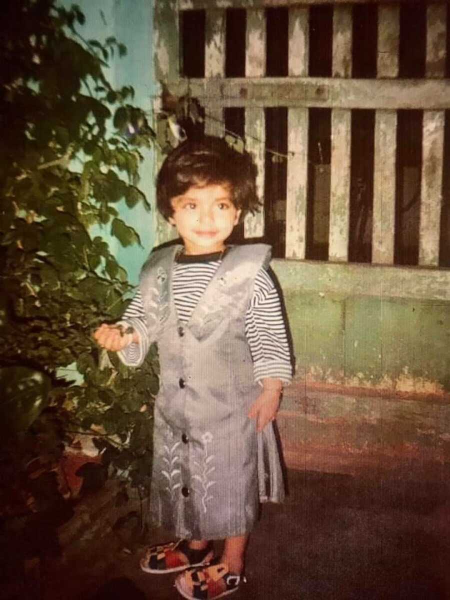 little girl standing by a tree