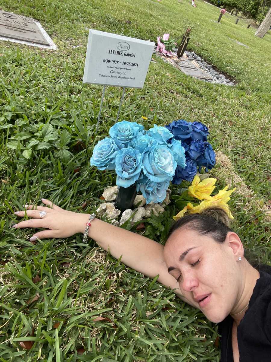 woman laying down at husbands grave