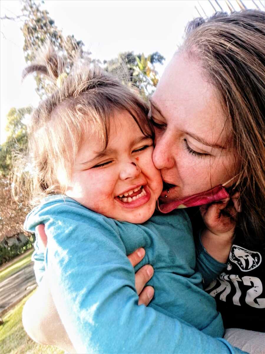 mom kissing her daughter on the cheek