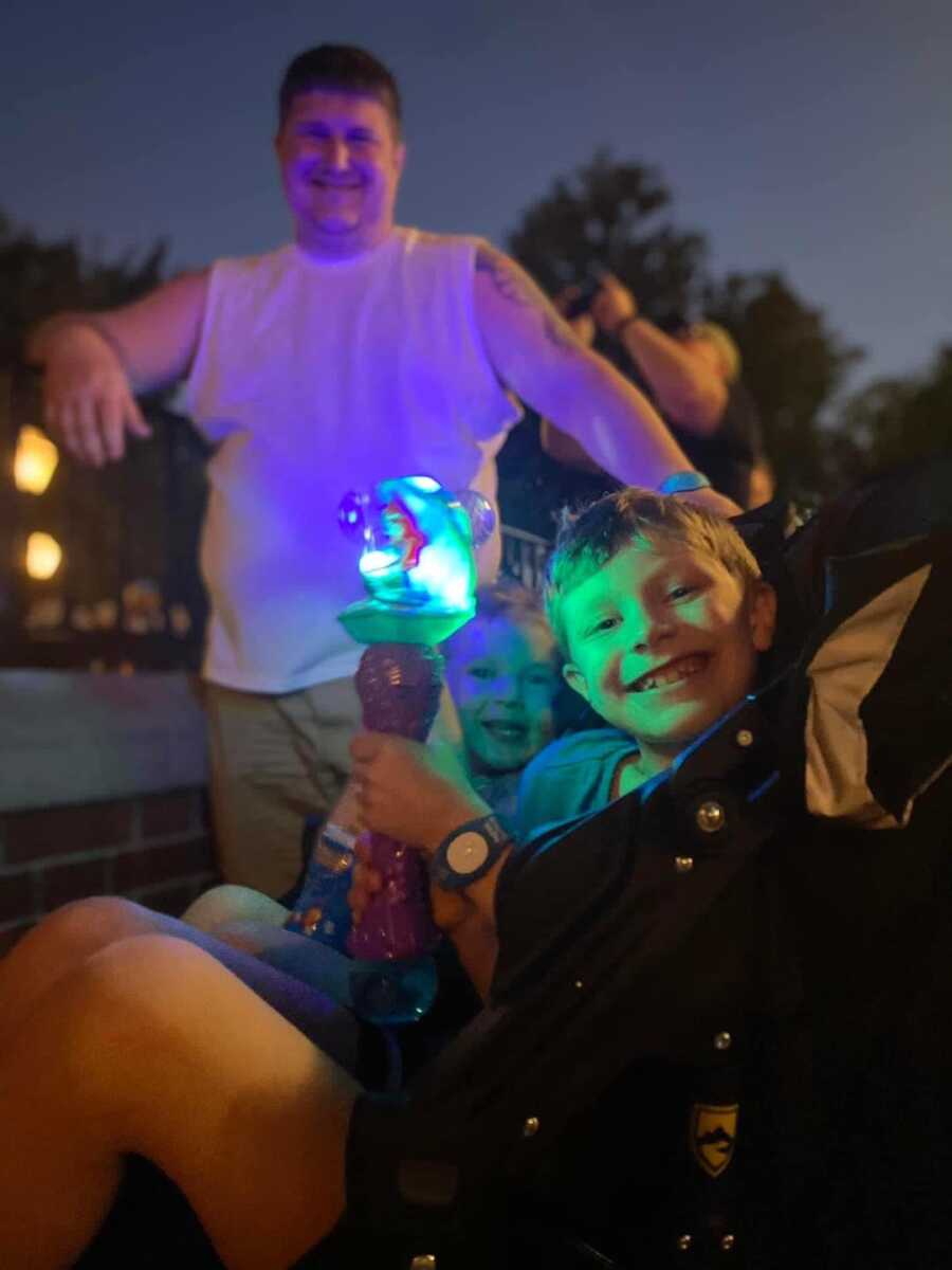two boys smiling holding a light up toy