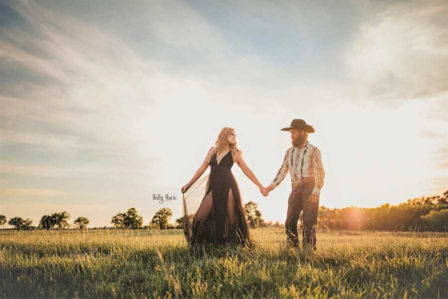 Husband and wife walking on a field holding each other's hands