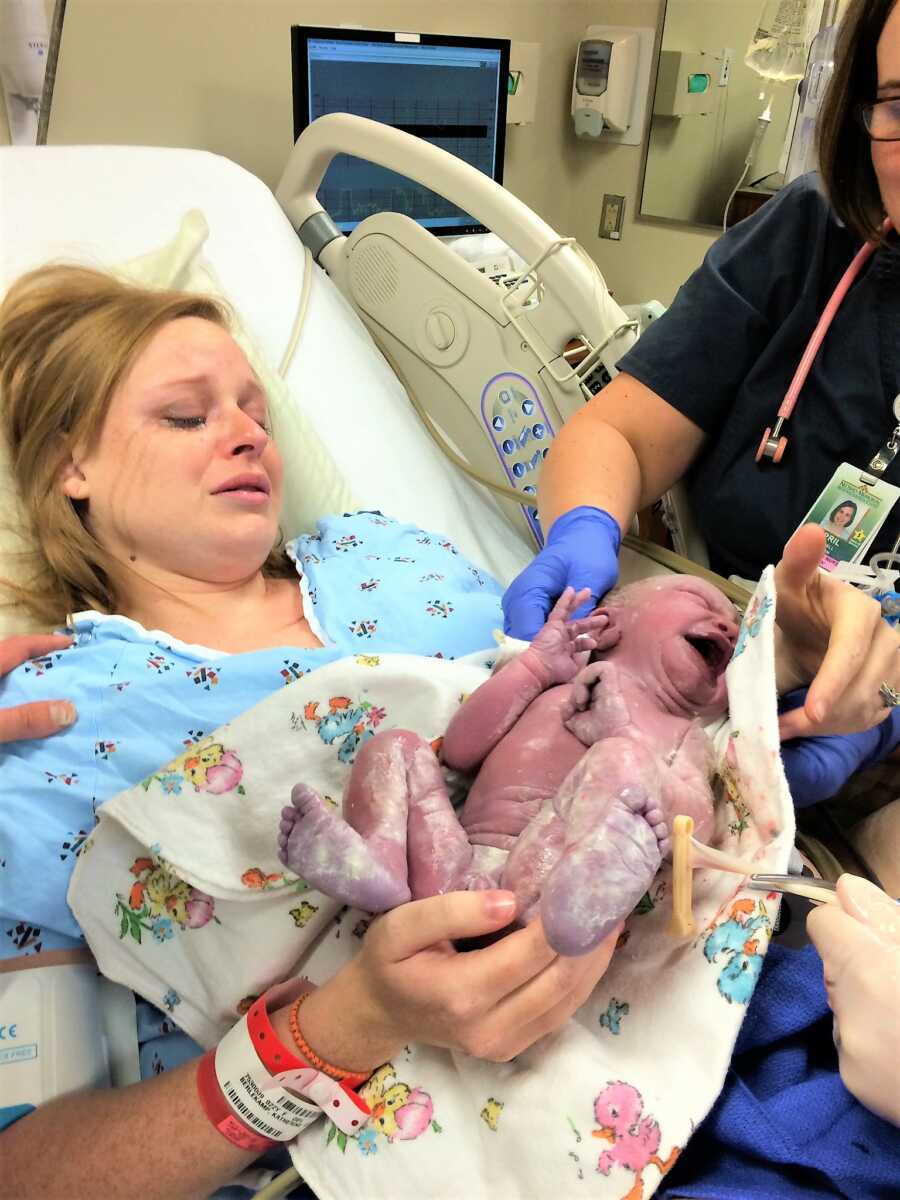mom with tears in her eyes while holding her newborn daughter for the first time
