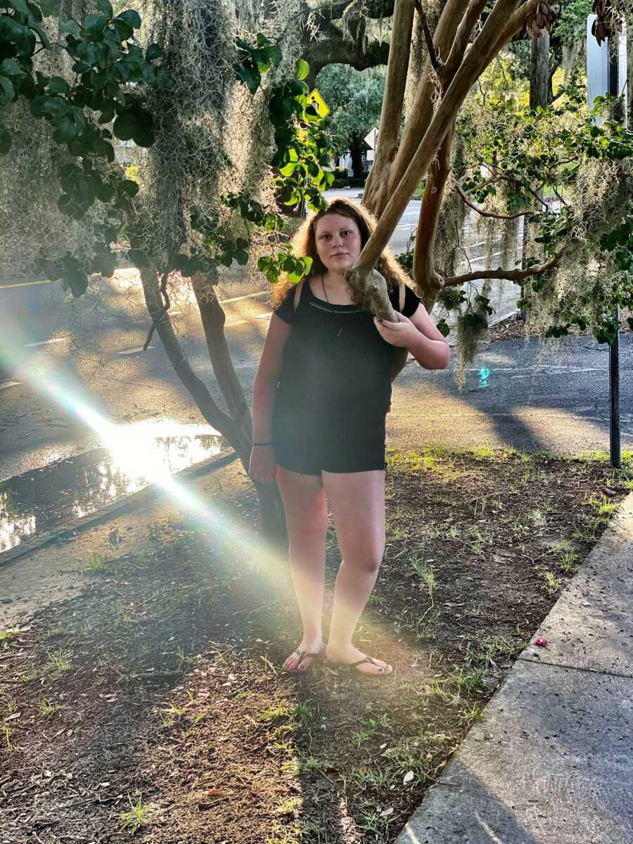 Teen foster girl poses beneath a tree.