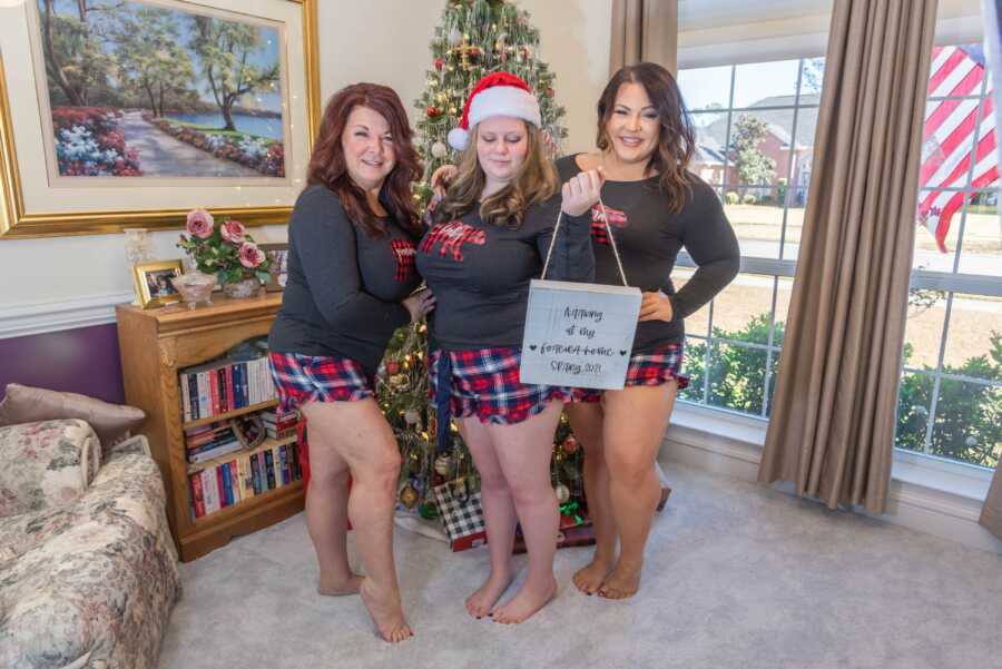 Adoptive mom, grandma, and teen daughter take picture in matching Christmas pajamas.