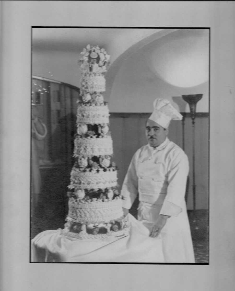black and white photo of man with a large cake 