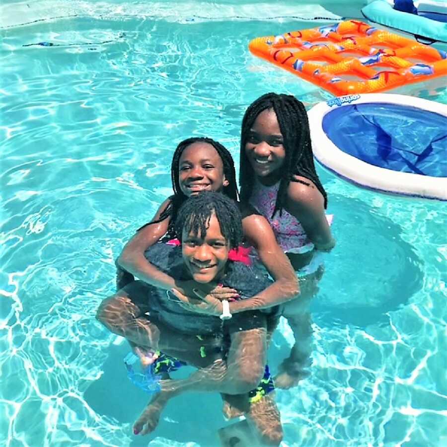 Three Haitian kids playing at the pool on a sunny day