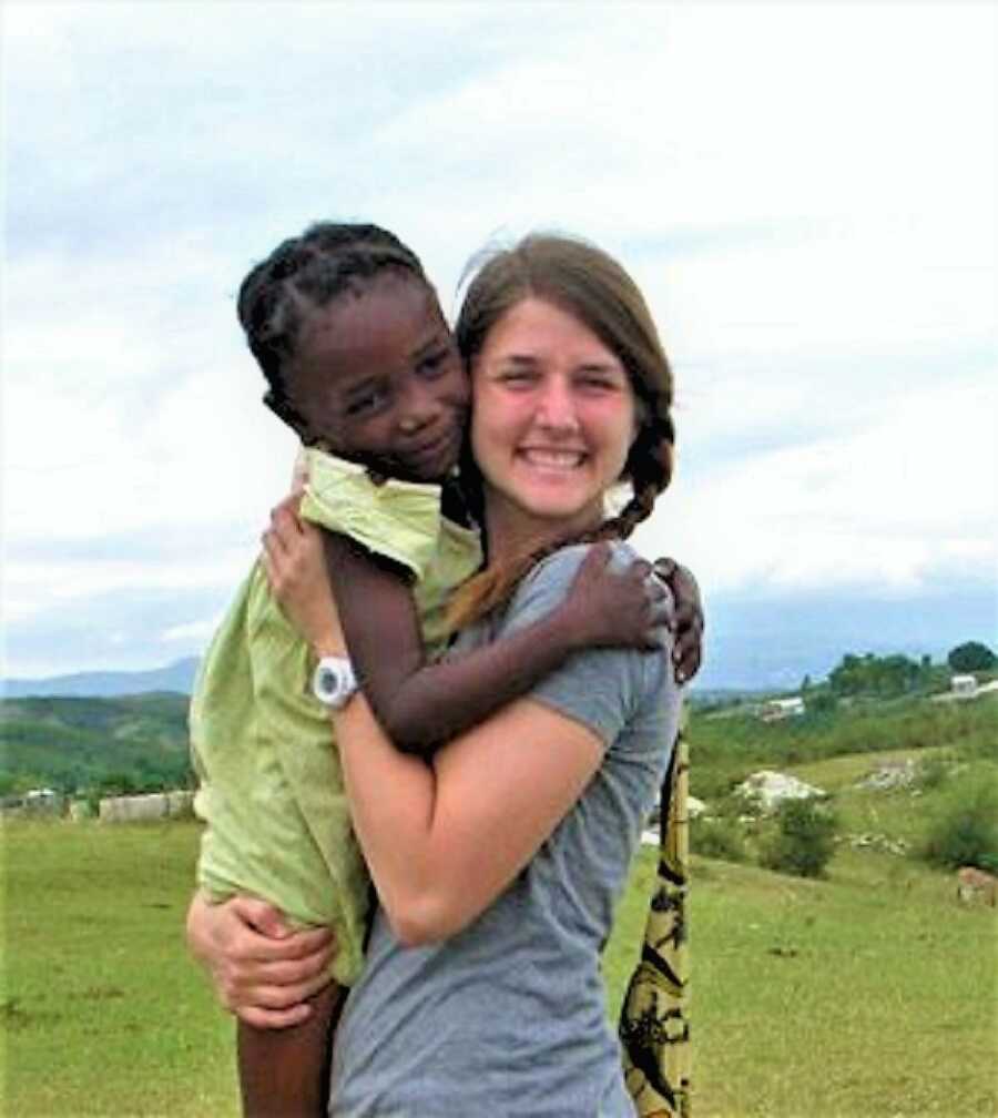 White woman holding a young Haitian girl in her arms in the mountains of Haiti 