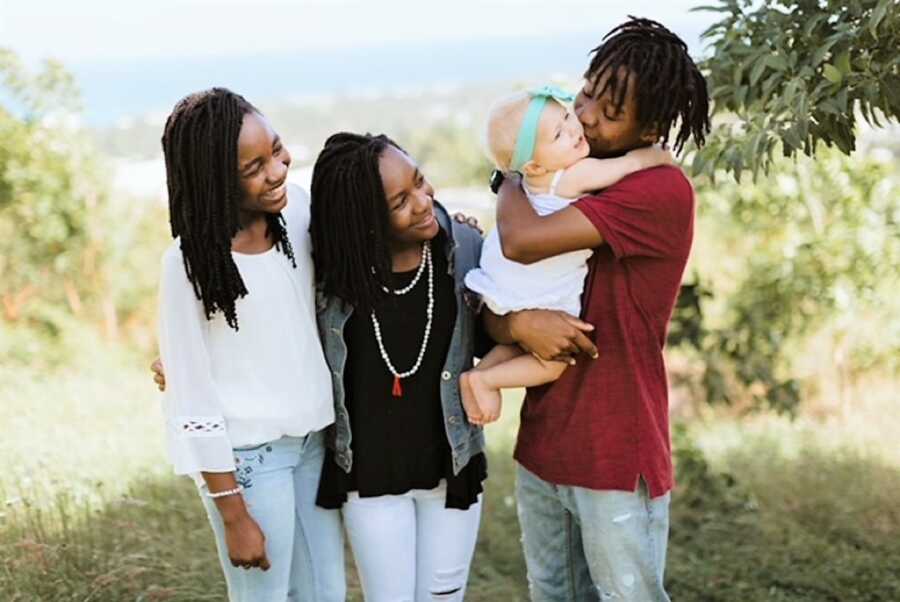 Three older siblings holing their new baby sister 