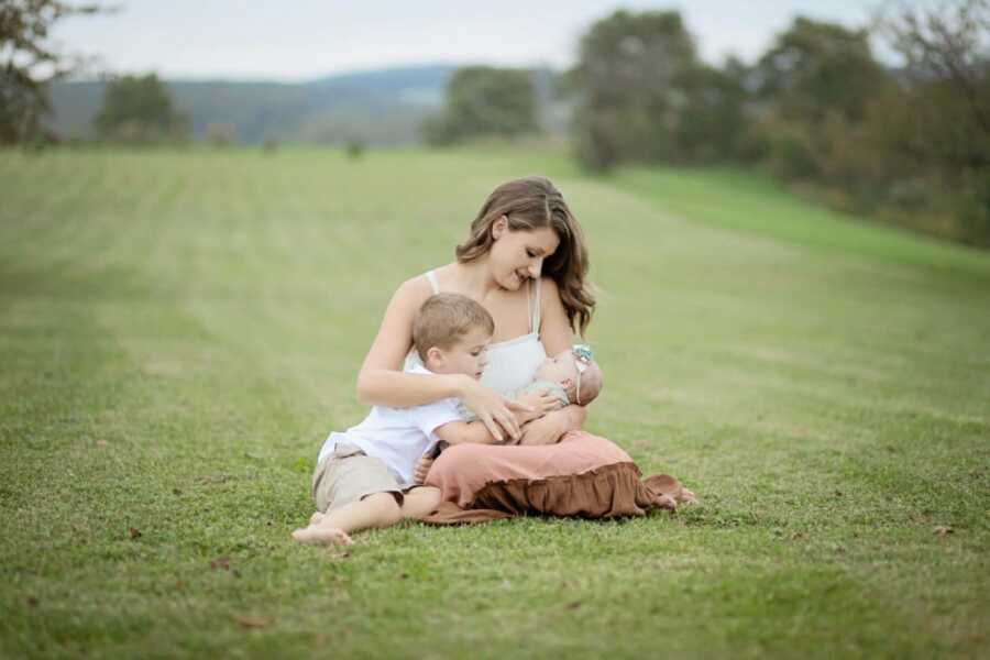 Sober mom of two takes a photo with her son and newborn daughter in a field