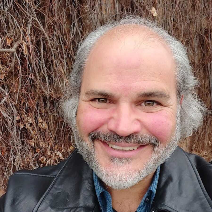 man standing in woods taking selfie smiling 