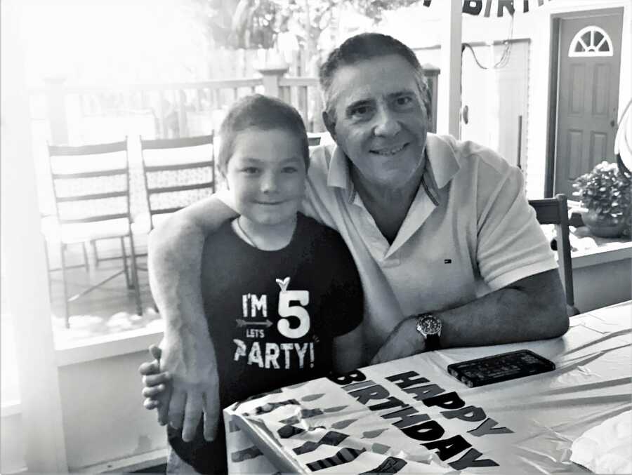 Step-grandpa sitting next to his step-grandson with his arm around the boy's shoulder