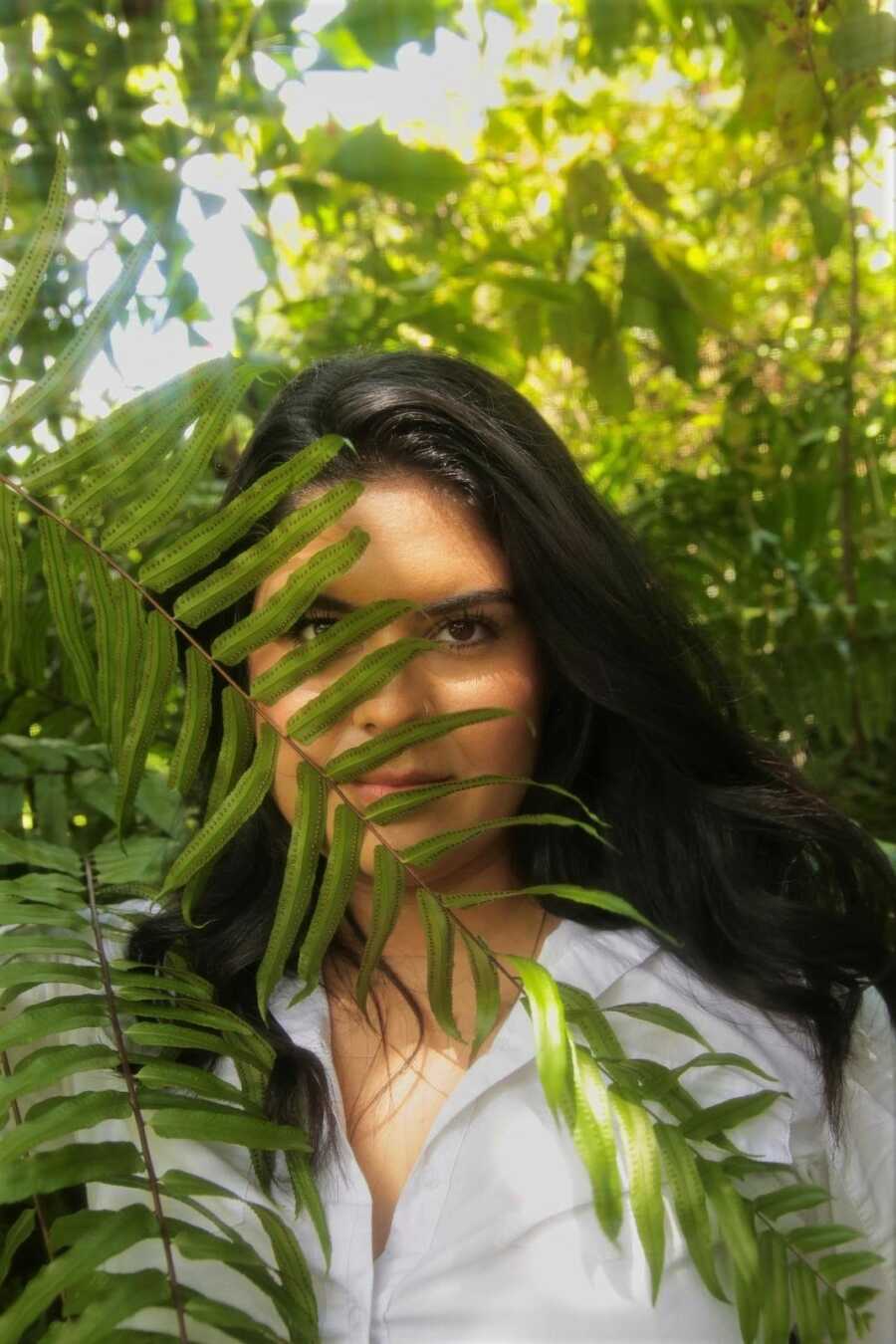 woman hiding behind a leaf in the sun