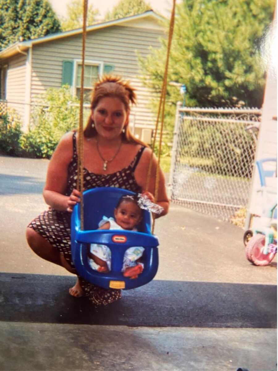 Single mom struggling with alcohol addiction pushes baby girl in plastic swing.