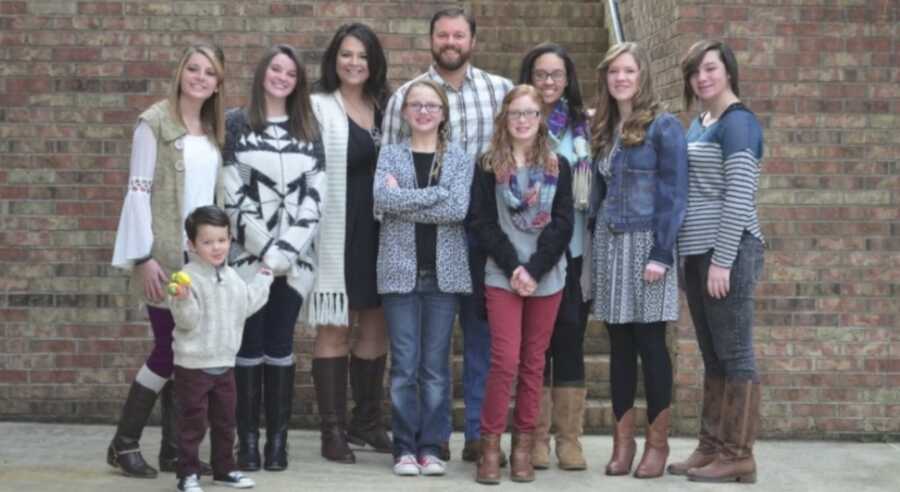 Teen girl takes family picture with her first foster family.