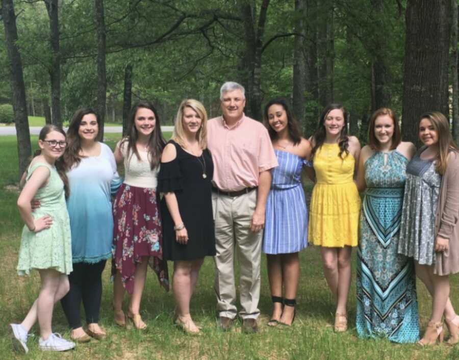 Teen girl takes picture with her second foster family.