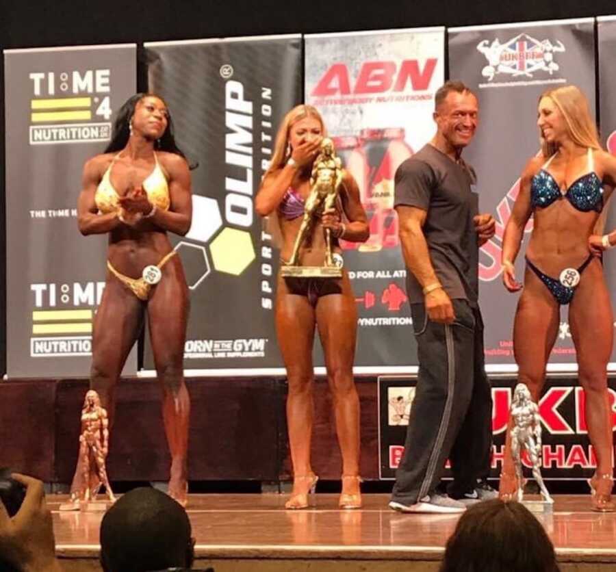 women standing on stage with trophy