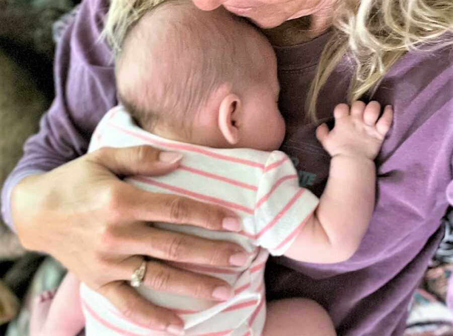 First-time grandmother holding her newborn granddaughter on her chest 