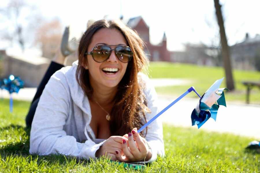 woman with pinwheel in her hands smiling with sunglasses on 