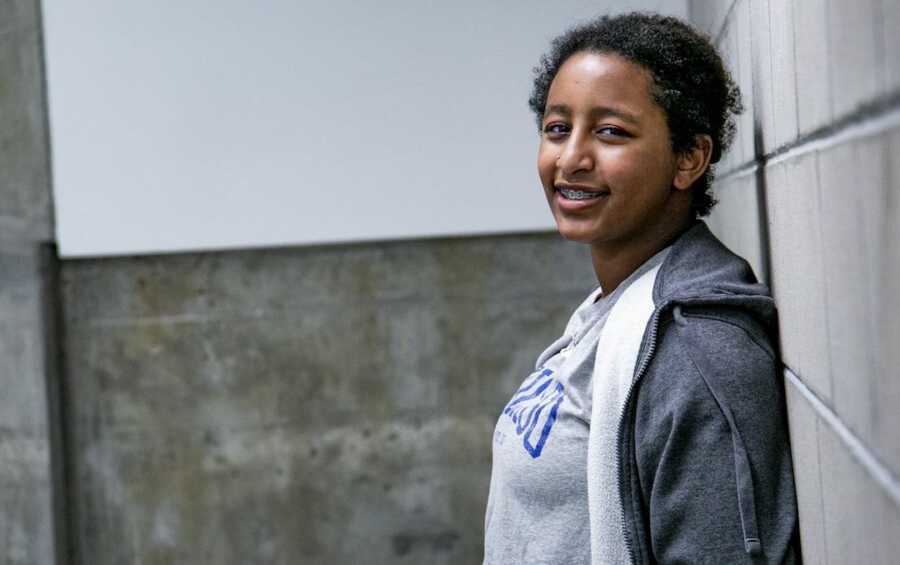 oldest daughter standing against wall smiling 