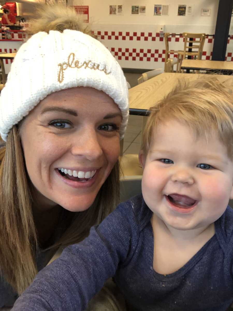 Mom wearing Plexus beanie smiles next to chubby baby boy.