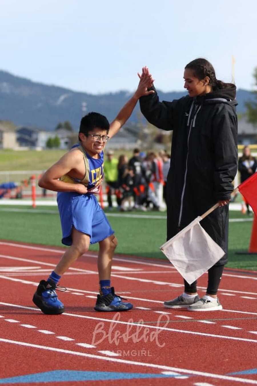 Young high school track athlete high fives coach.