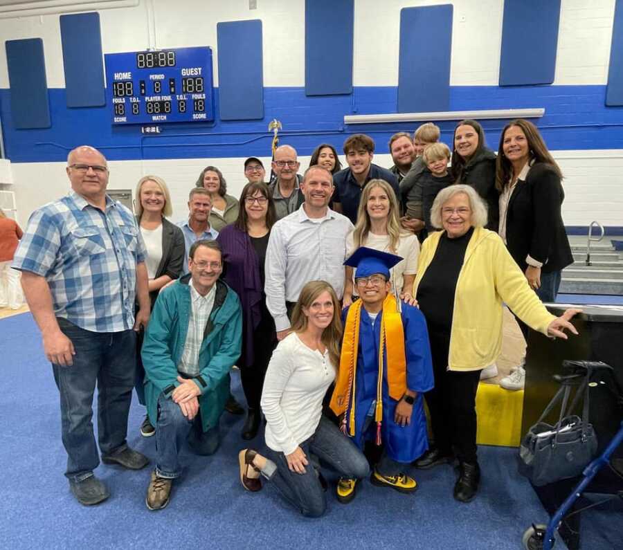 Young man takes picture with family and friends at high school graduation.