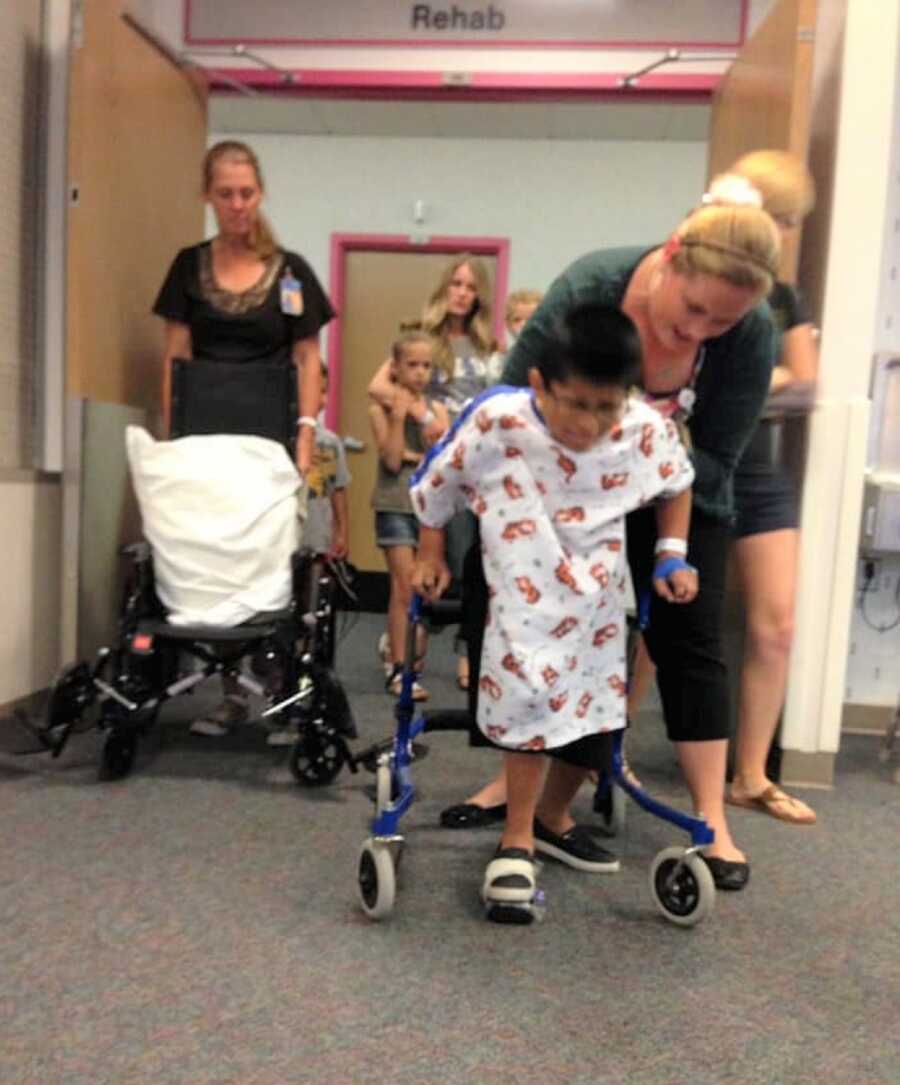 Young boy with spina bifida uses walker after surgery.