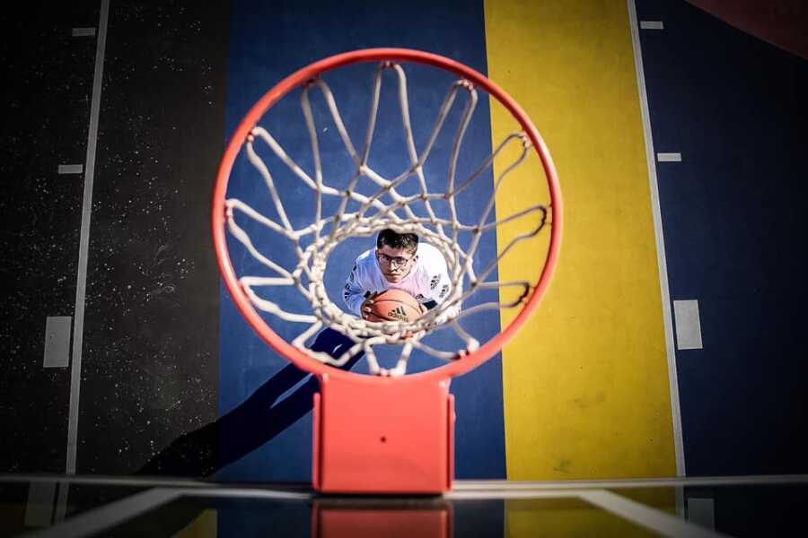 Bird's eye view of young man with spina bifida under basketball hoop.