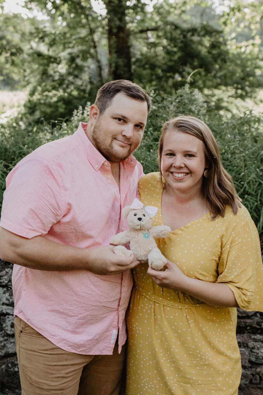 parents hold a stuffed bear in honor of their daughter lost during pregnancy