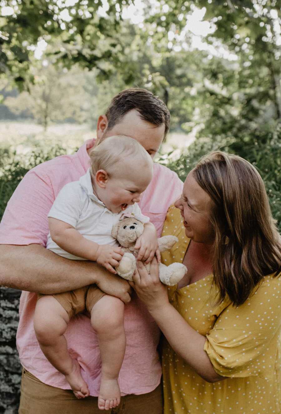 parents hold up son who is holding teddybear honoring daughter they lost