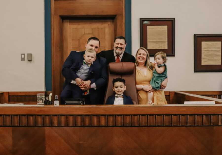 family stands with judge on the stand on the day of their son's adoption