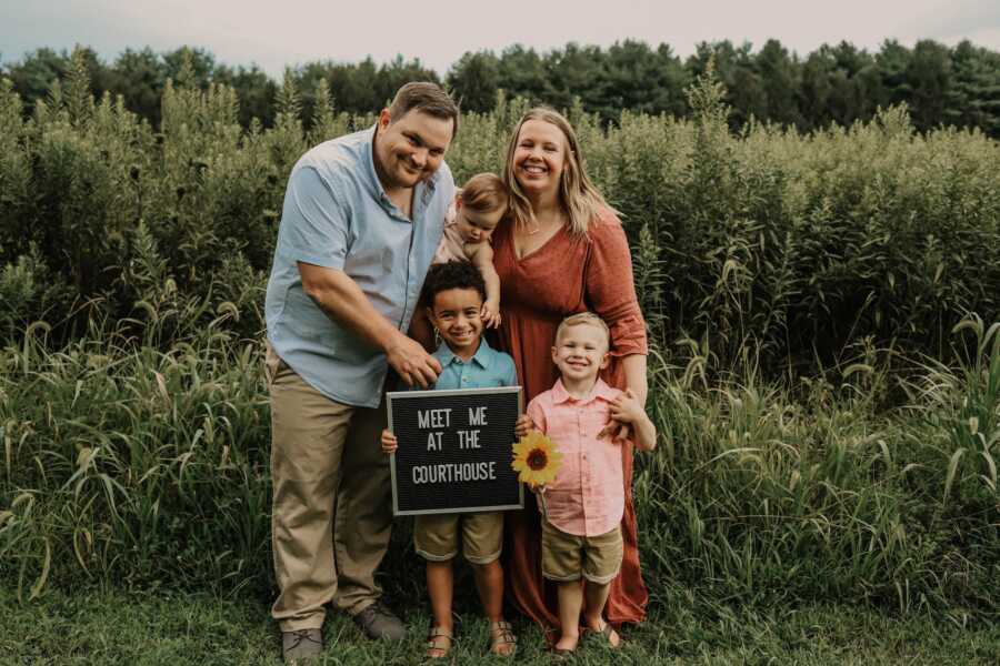 family consisting of biological children and adopted son stand together smiling