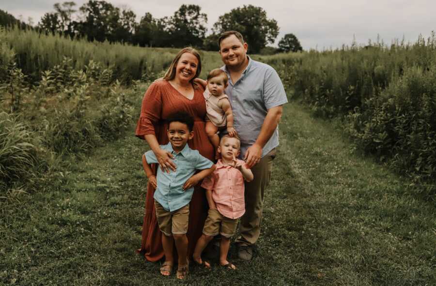 mother holds baby and stands with husband and two other children