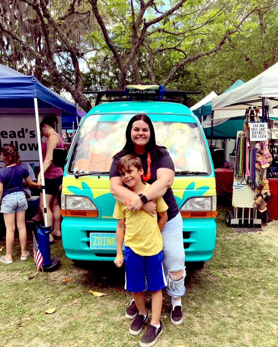 mom stands with her son in front of a Scooby Doo bus