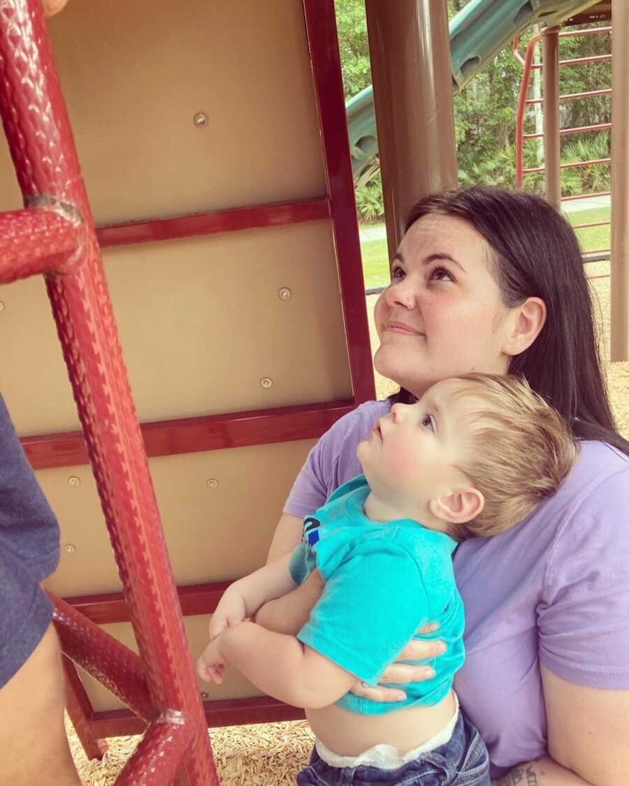 mom holds son while both are looking up