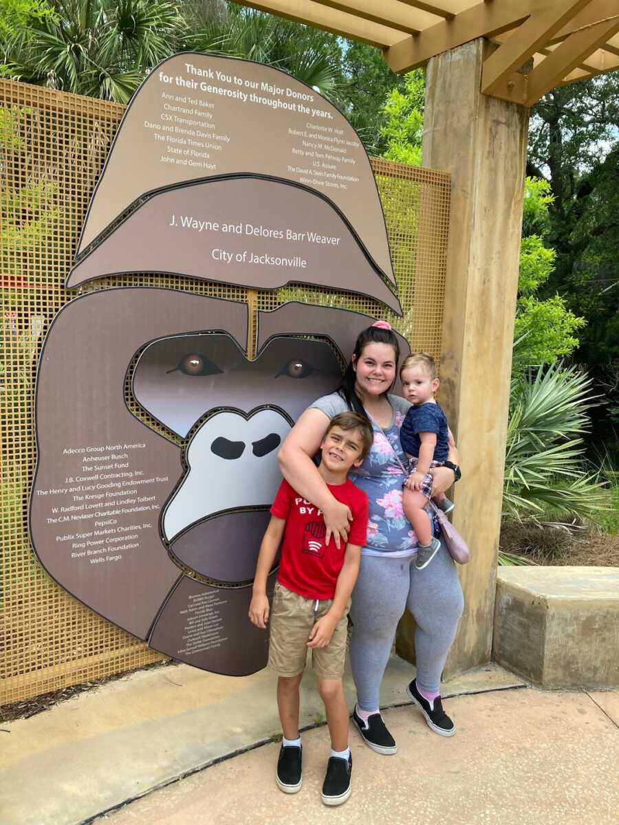 mom stands with her two sons while at the zoo