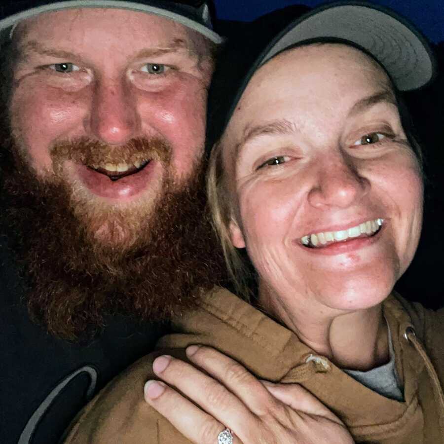 A man and woman smile widely in a selfie