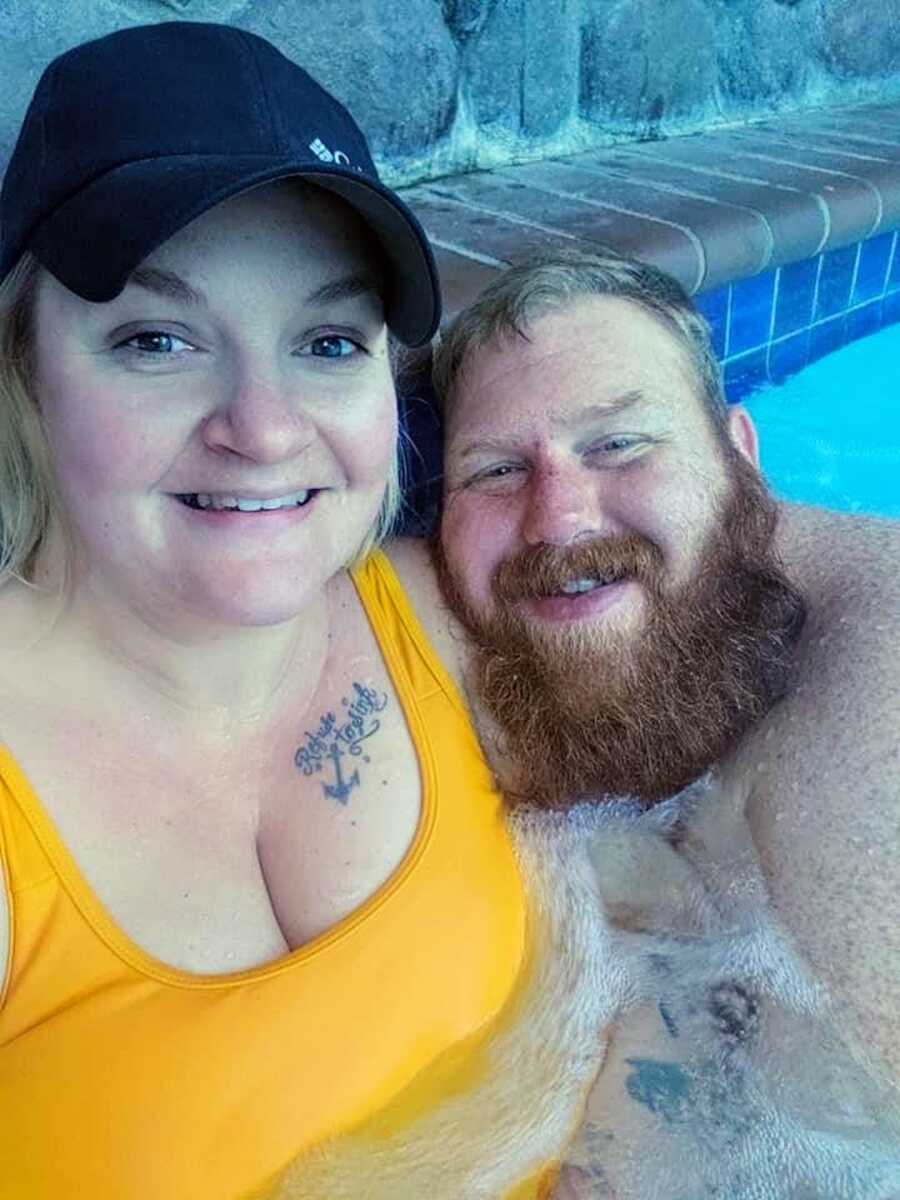 A man and woman smile in a pool