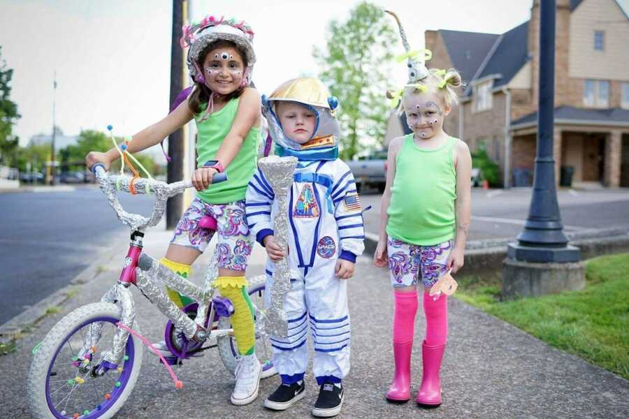 Three children are dressed up outside