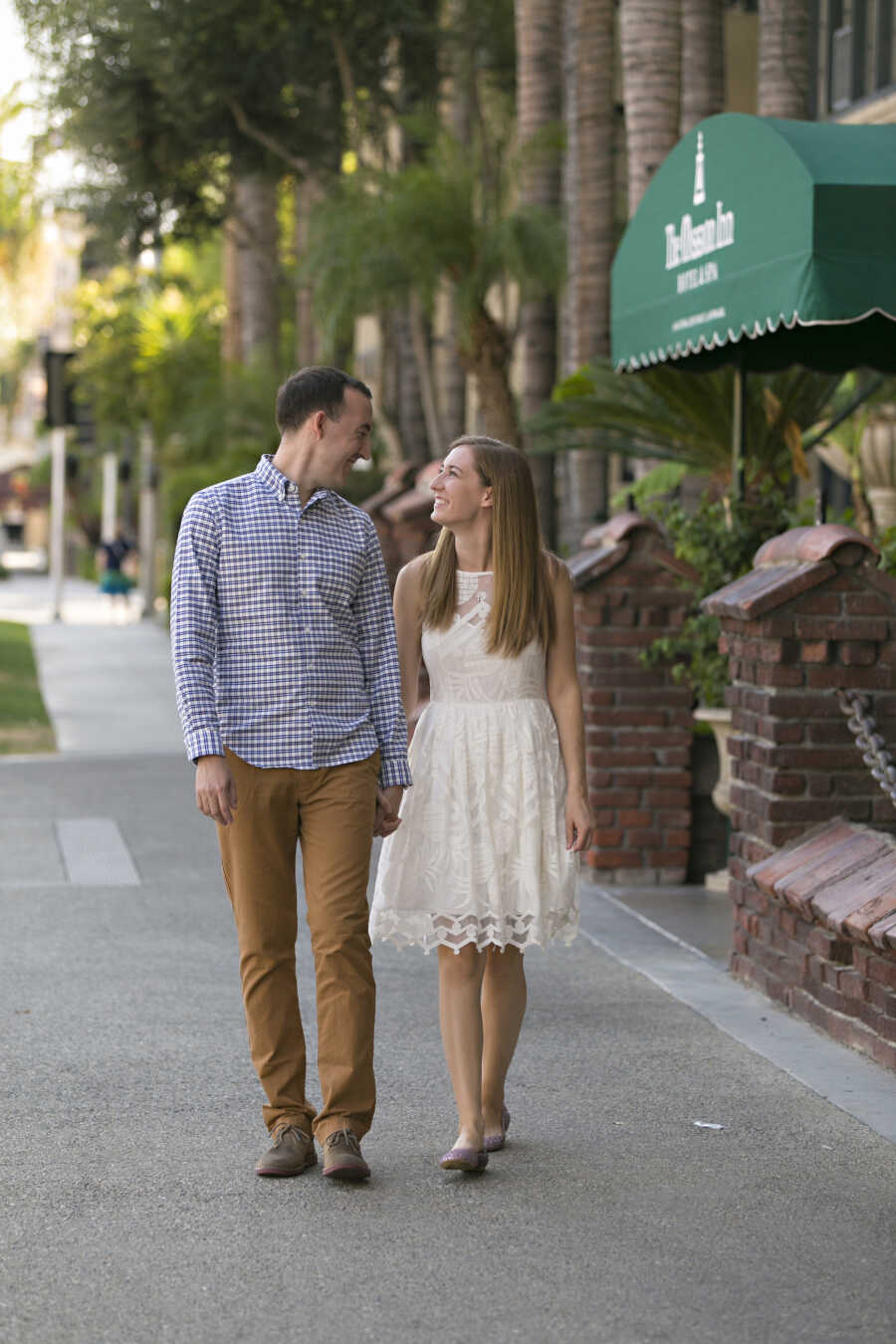 Young couple walks down the street holding hands and looking at each other.