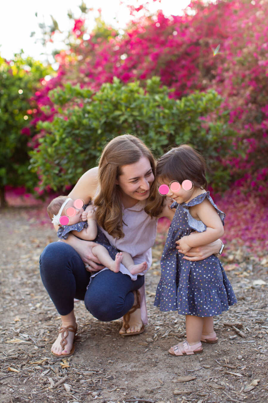 Foster mom takes picture with young foster girl crouching down outside.