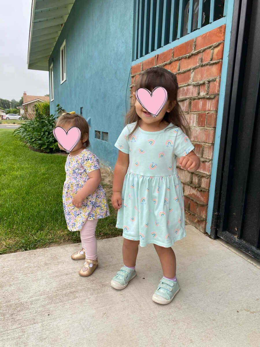 Baby sisters in foster care take picture in cute dresses standing in front of house.