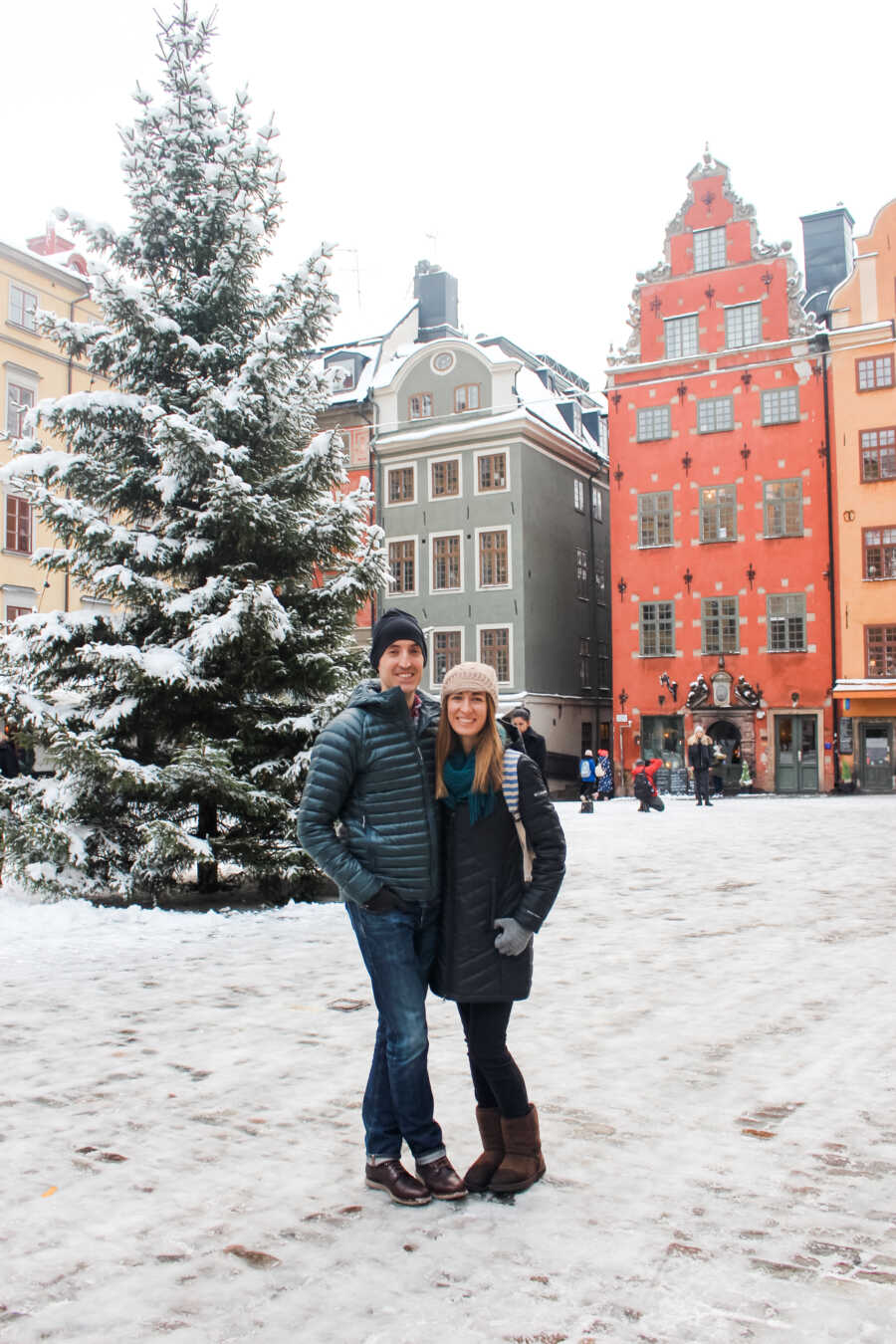 Young couple take winter picture standing outside in the snow on one of their many adventures together.