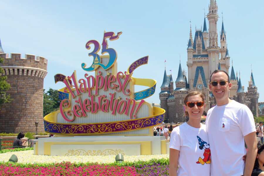 Couple take picture together in front of Disneyland castle.