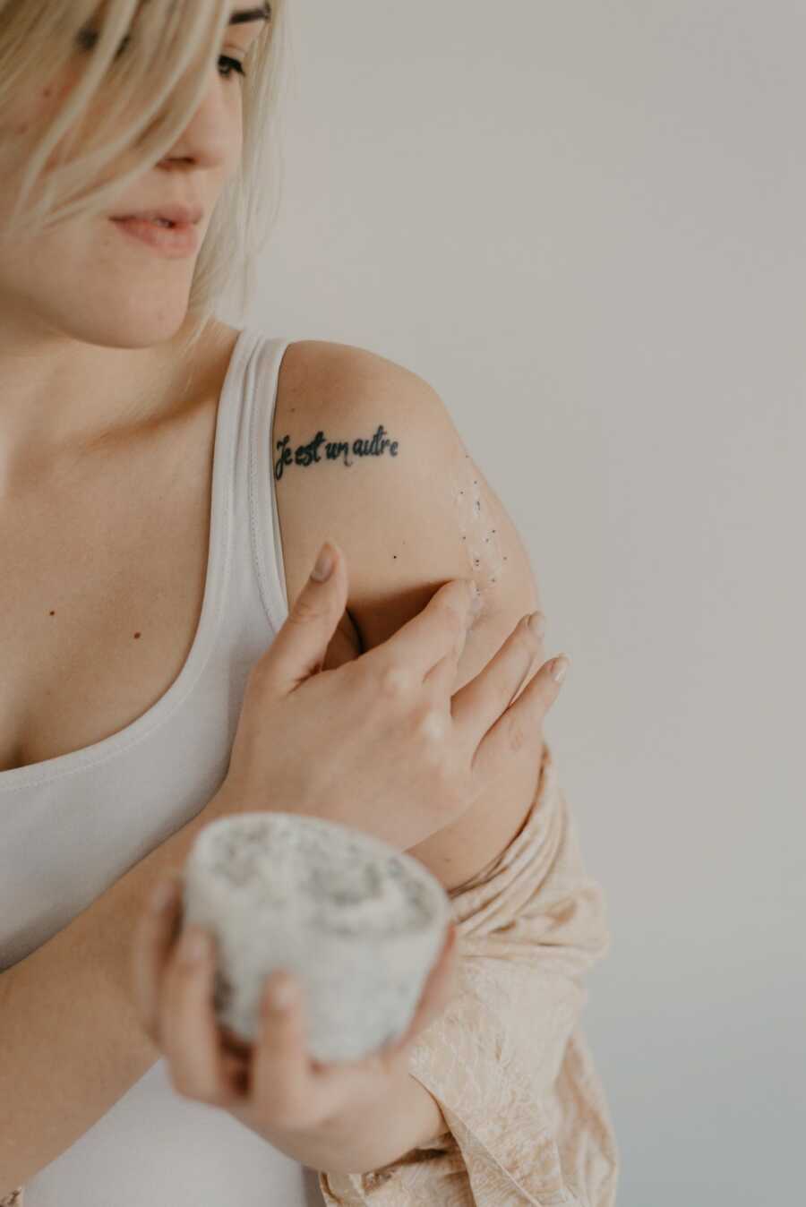 Woman applies lotion to her shoulder